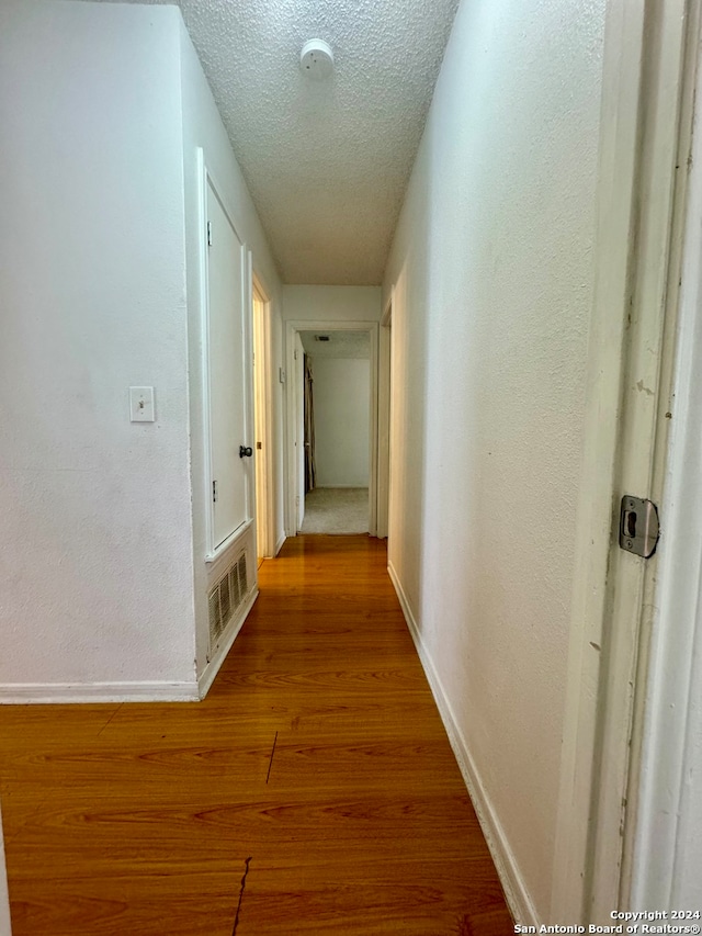 hallway featuring a textured ceiling and light hardwood / wood-style floors