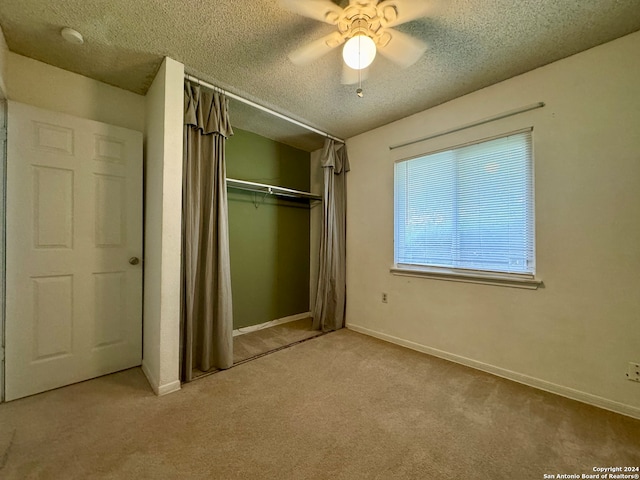 unfurnished bedroom with ceiling fan, a closet, light colored carpet, and a textured ceiling