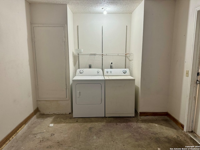 washroom featuring washing machine and clothes dryer and a textured ceiling