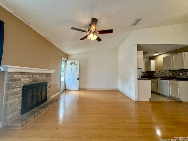 unfurnished living room featuring light hardwood / wood-style flooring, a brick fireplace, ceiling fan, and lofted ceiling