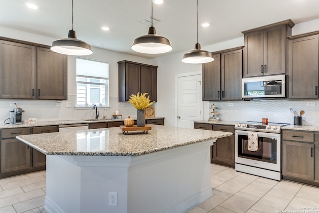 kitchen with appliances with stainless steel finishes, light stone countertops, pendant lighting, decorative backsplash, and a kitchen island