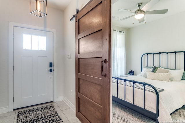 entrance foyer featuring ceiling fan, a barn door, and light tile patterned floors