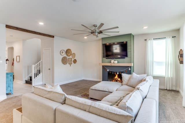 living room with a large fireplace, ceiling fan, and light carpet