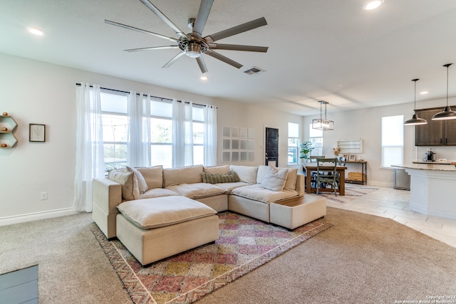 carpeted living room featuring ceiling fan with notable chandelier