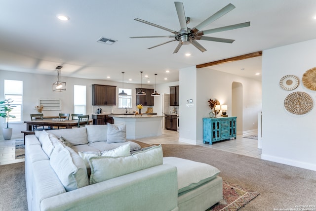 living room with light colored carpet, ceiling fan, and beamed ceiling