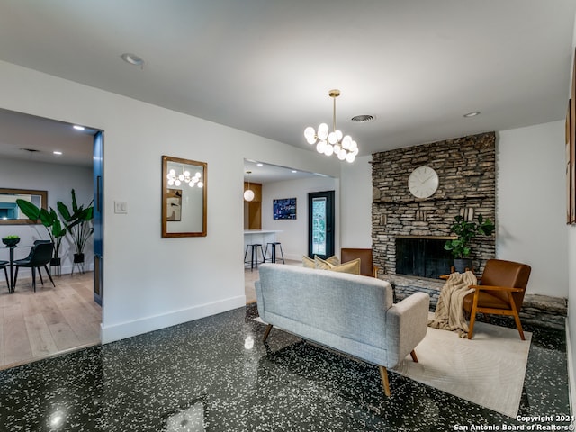 living room with hardwood / wood-style floors, a notable chandelier, and a stone fireplace