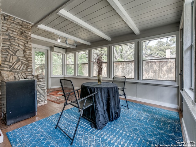 sunroom with a wall mounted air conditioner, beam ceiling, and a healthy amount of sunlight