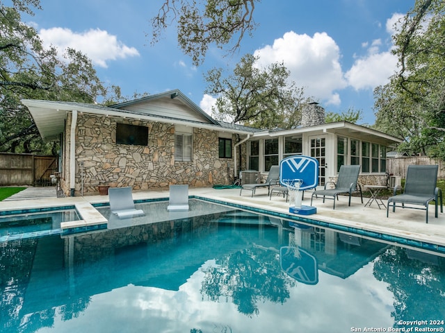 back of house featuring a sunroom, a patio, and a swimming pool with hot tub