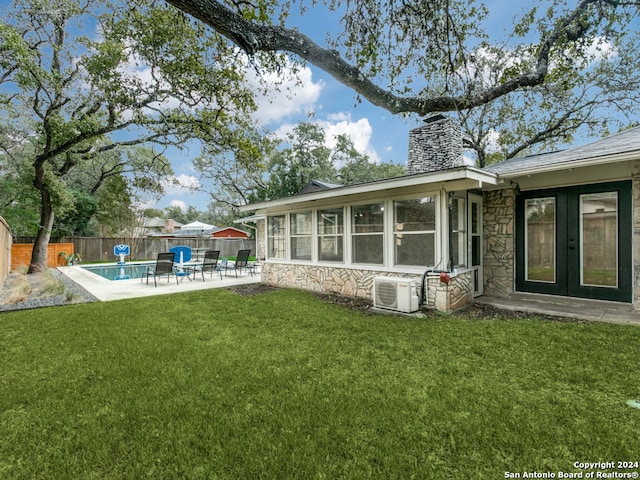 back of house with french doors, ac unit, a patio, a fenced in pool, and a lawn