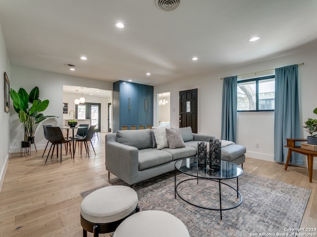 living room with light hardwood / wood-style floors, an inviting chandelier, and a healthy amount of sunlight