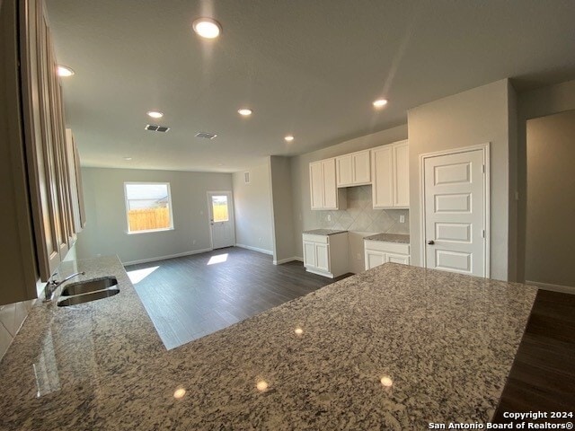 kitchen with white cabinets, stone countertops, dark hardwood / wood-style floors, and sink