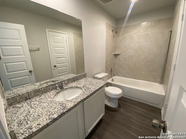 full bathroom featuring toilet, vanity, wood-type flooring, and tiled shower / bath