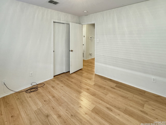 unfurnished bedroom featuring light hardwood / wood-style flooring and a closet