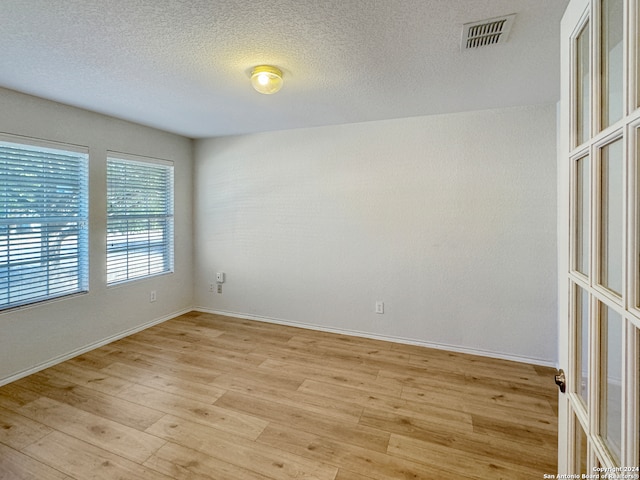 spare room featuring light hardwood / wood-style flooring and a textured ceiling