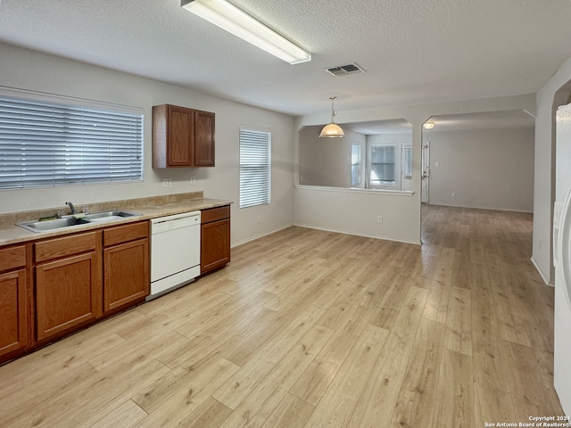 kitchen featuring decorative light fixtures, light hardwood / wood-style flooring, dishwasher, and sink