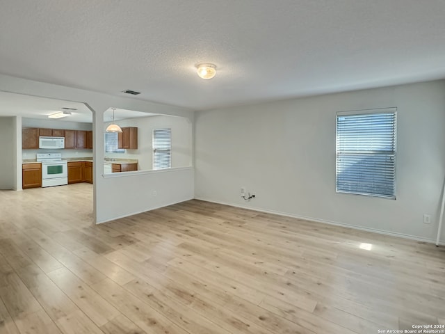 unfurnished living room featuring a textured ceiling and light hardwood / wood-style flooring