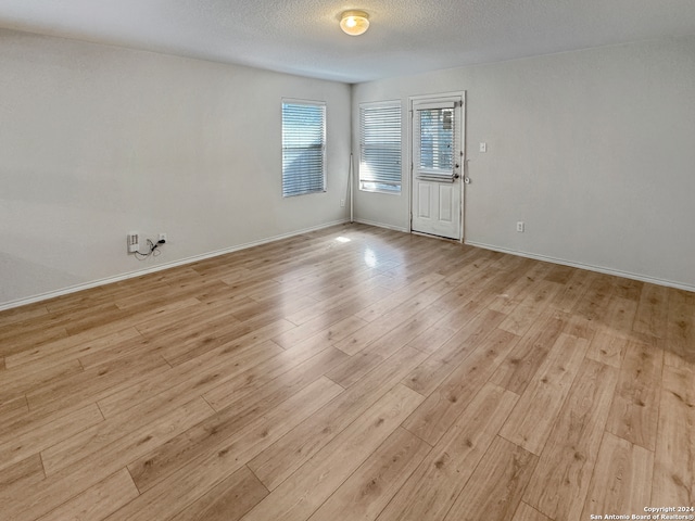 empty room with a textured ceiling and light wood-type flooring