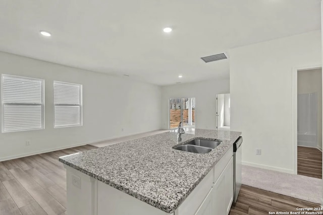 kitchen with light stone countertops, white cabinetry, sink, stainless steel dishwasher, and light hardwood / wood-style floors