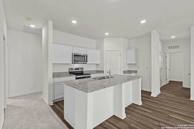 kitchen with stainless steel appliances, white cabinetry, a center island with sink, and light stone counters