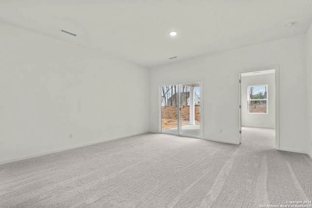 unfurnished room with light colored carpet and plenty of natural light