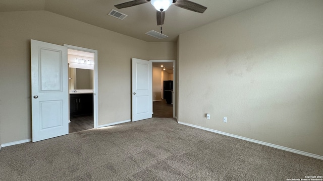 unfurnished bedroom with dark colored carpet, ensuite bath, ceiling fan, and lofted ceiling