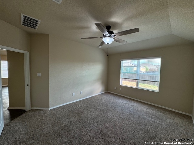 unfurnished room featuring a textured ceiling, ceiling fan, dark carpet, and lofted ceiling