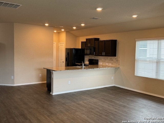 kitchen featuring light stone counters, dark hardwood / wood-style floors, backsplash, kitchen peninsula, and black appliances