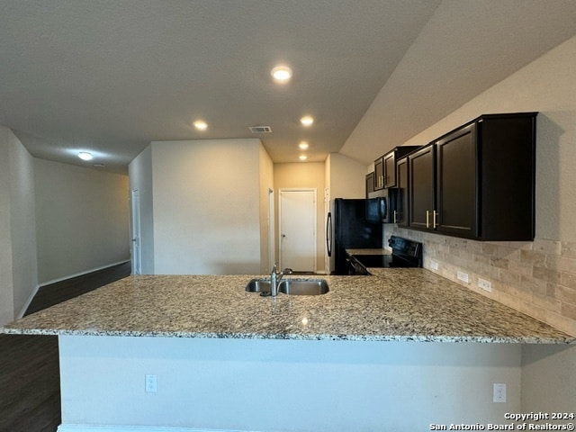 kitchen featuring light stone countertops, sink, kitchen peninsula, decorative backsplash, and appliances with stainless steel finishes