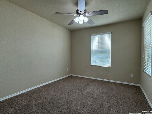 unfurnished room with a textured ceiling, dark carpet, and ceiling fan