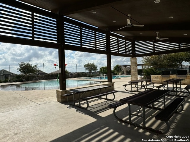 view of patio featuring ceiling fan, a community pool, and an outdoor kitchen