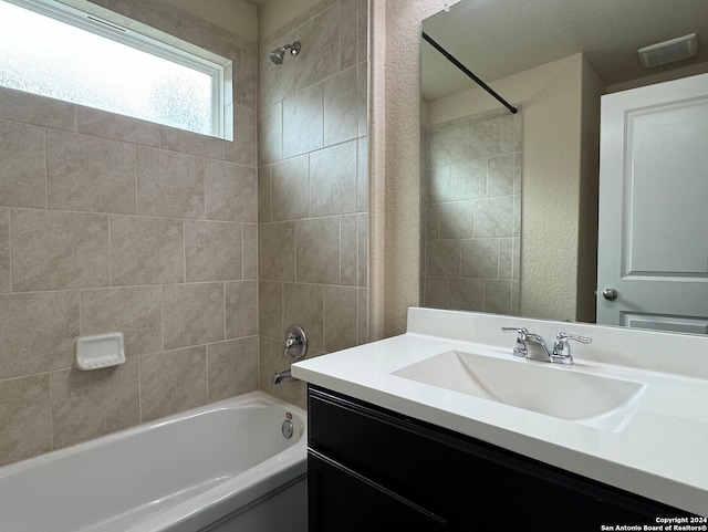 bathroom featuring tiled shower / bath combo and vanity