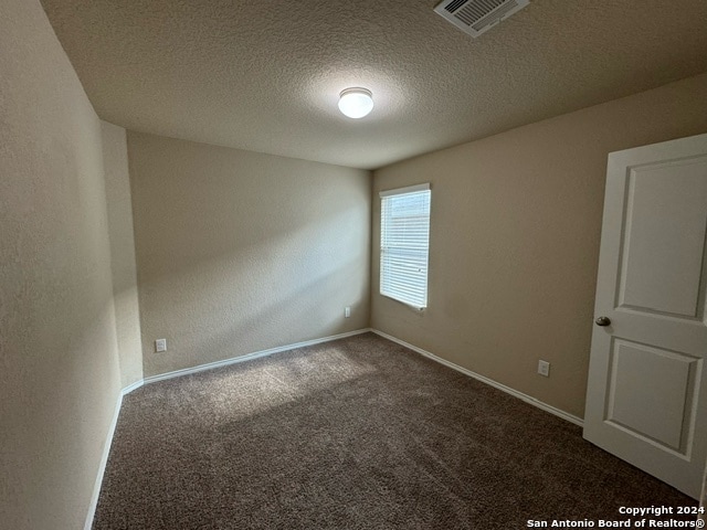 carpeted spare room with a textured ceiling