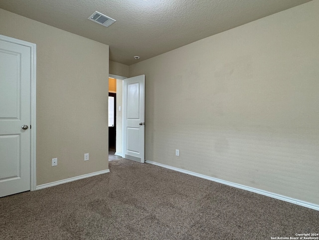 unfurnished room with a textured ceiling and dark carpet