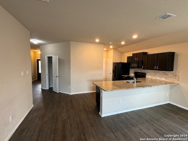 kitchen featuring kitchen peninsula, decorative backsplash, light stone countertops, dark wood-type flooring, and black appliances