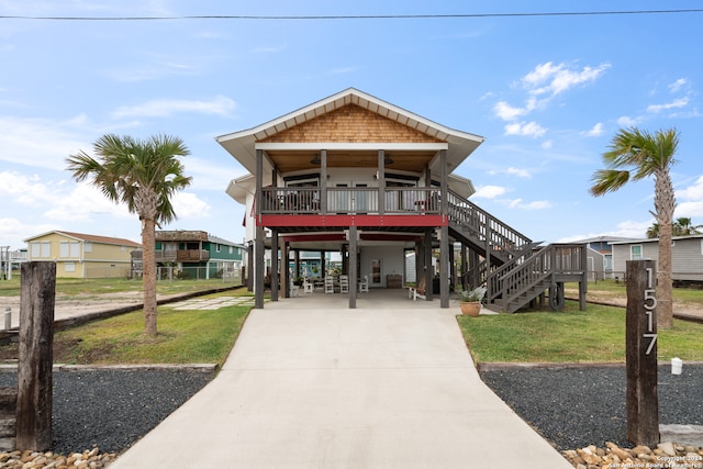 raised beach house with a front lawn, covered porch, and a carport