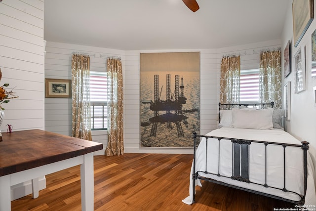 1517 S Magnolia St, Rockport, TX 78382 - bedroom featuring wood finished floors, multiple windows, wooden walls, and a ceiling fan