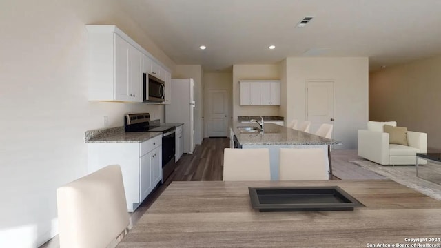 923 Middlebury Farms, San Antonio, TX 78221 - kitchen featuring stainless steel appliances, light stone countertops, a sink, wood finished floors, and white cabinetry