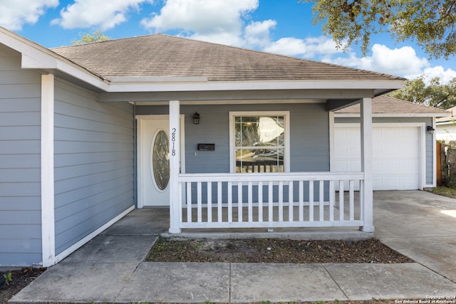 doorway to property with covered porch and a garage