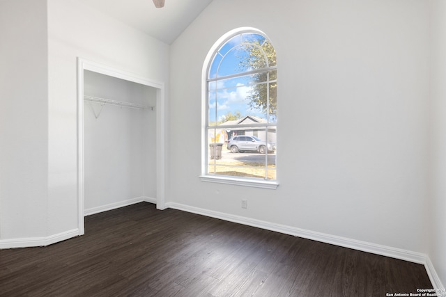 unfurnished bedroom featuring ceiling fan, a closet, dark wood-type flooring, and lofted ceiling