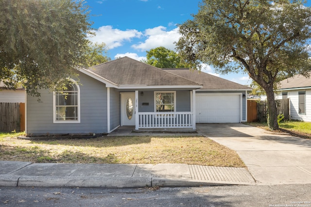 single story home with a front lawn, covered porch, and a garage