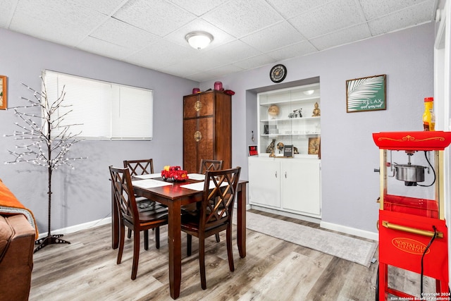 dining space featuring independent washer and dryer, a drop ceiling, and light wood-type flooring