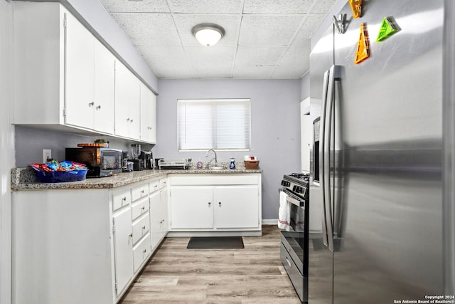 kitchen featuring a paneled ceiling, white cabinetry, light wood-type flooring, and appliances with stainless steel finishes