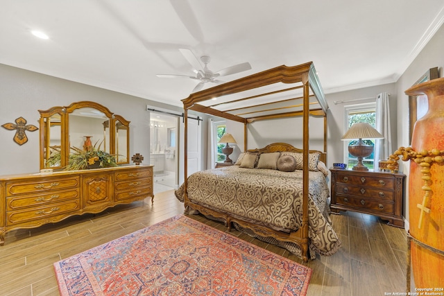 bedroom featuring connected bathroom, ceiling fan, wood-type flooring, and ornamental molding