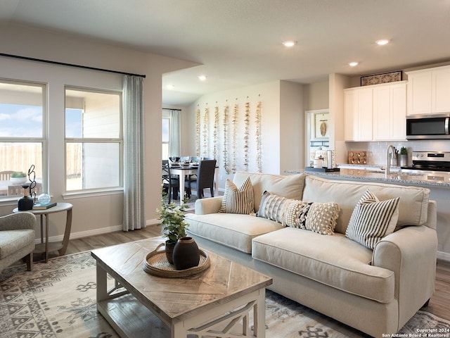 living area featuring baseboards, light wood-style flooring, and recessed lighting