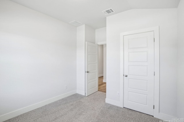 unfurnished bedroom with light carpet, baseboards, visible vents, and lofted ceiling