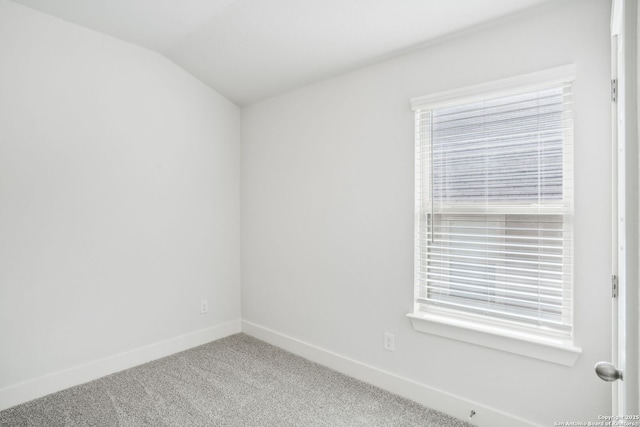 spare room featuring lofted ceiling, baseboards, and carpet flooring