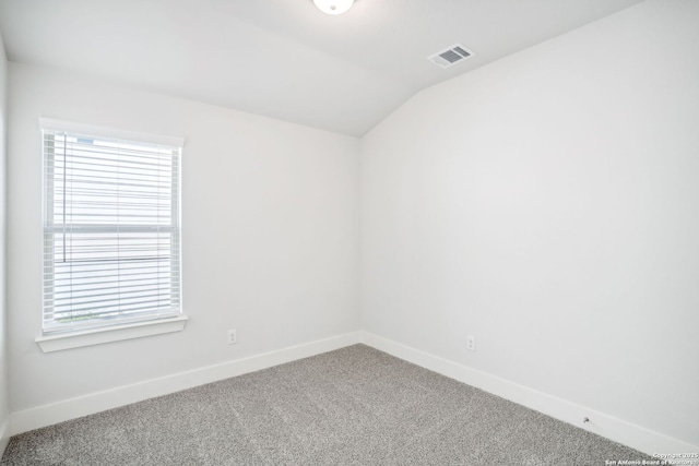 spare room with vaulted ceiling, carpet floors, visible vents, and baseboards