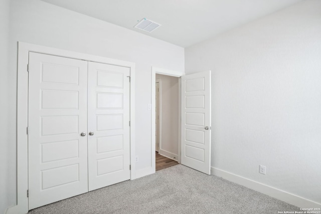 unfurnished bedroom featuring light carpet, a closet, visible vents, and baseboards