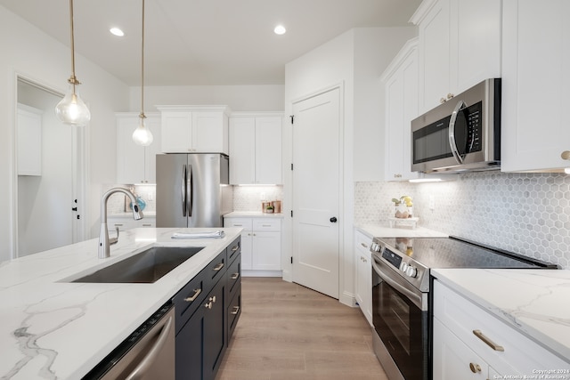 kitchen featuring light hardwood / wood-style flooring, white cabinets, sink, pendant lighting, and stainless steel appliances