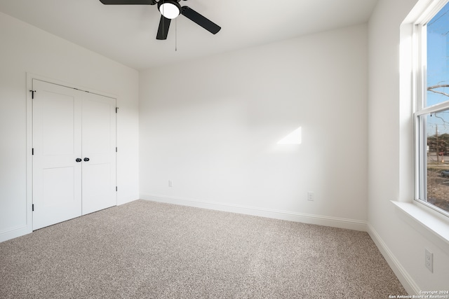 unfurnished bedroom with carpet flooring, a closet, multiple windows, and ceiling fan